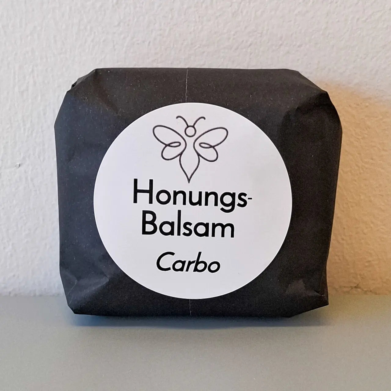 EneboBee handgjord balsamkaka 'HonungsBalsam Carbo' förpackad i svart papper med vit rund etikett.