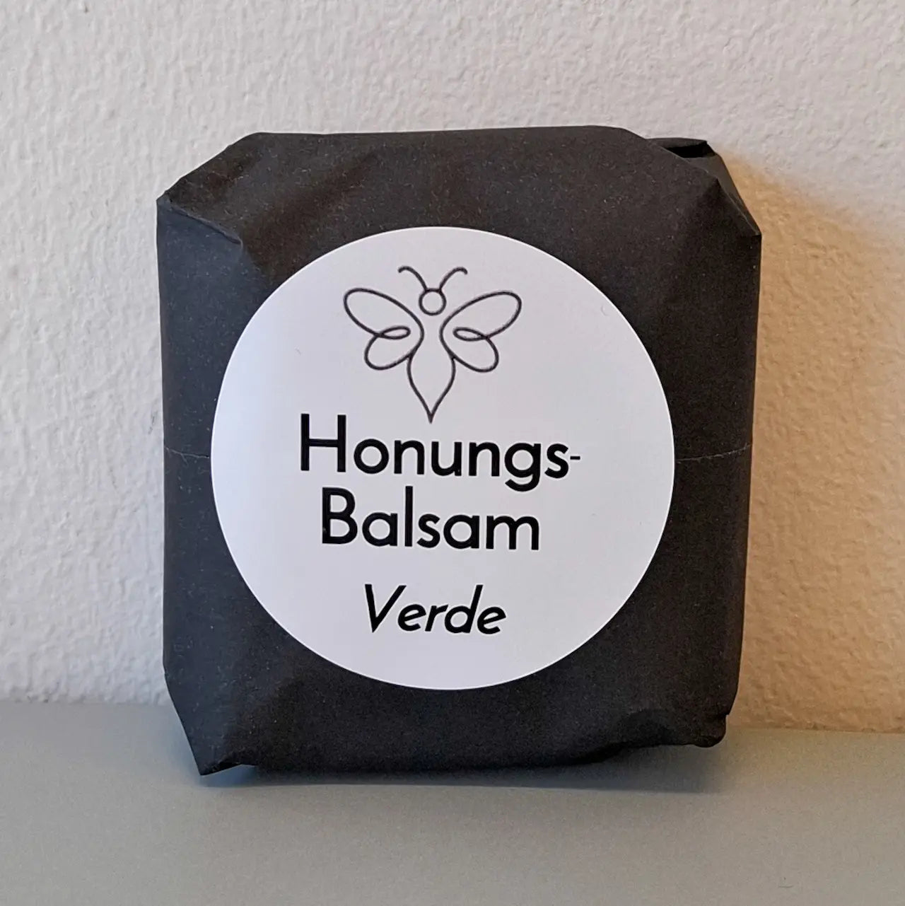 EneboBee handgjord balsamkaka 'HonungsBalsam Verde' förpackad i svart papper med vit rund etikett.
