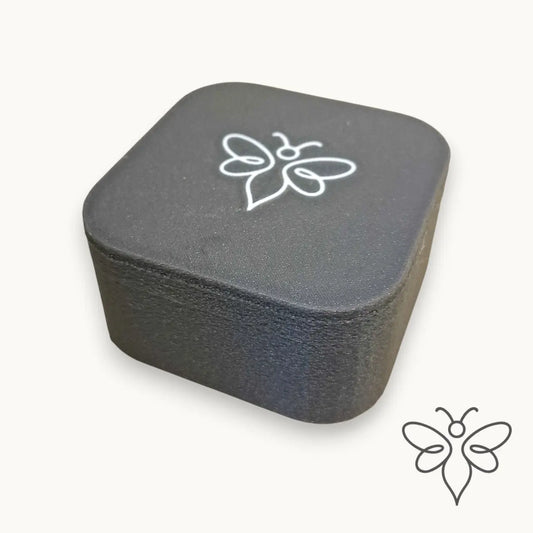 Grå förvaringsask i PETG för EneboBees balsamkakor, med vit bilogga på locket.