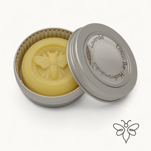 EneboBee Hudkrämskaka – Lotion Bar med bivax i doften Lavendel  i en öppnad metallburk med locket lutad mot en silverfärgad burk.