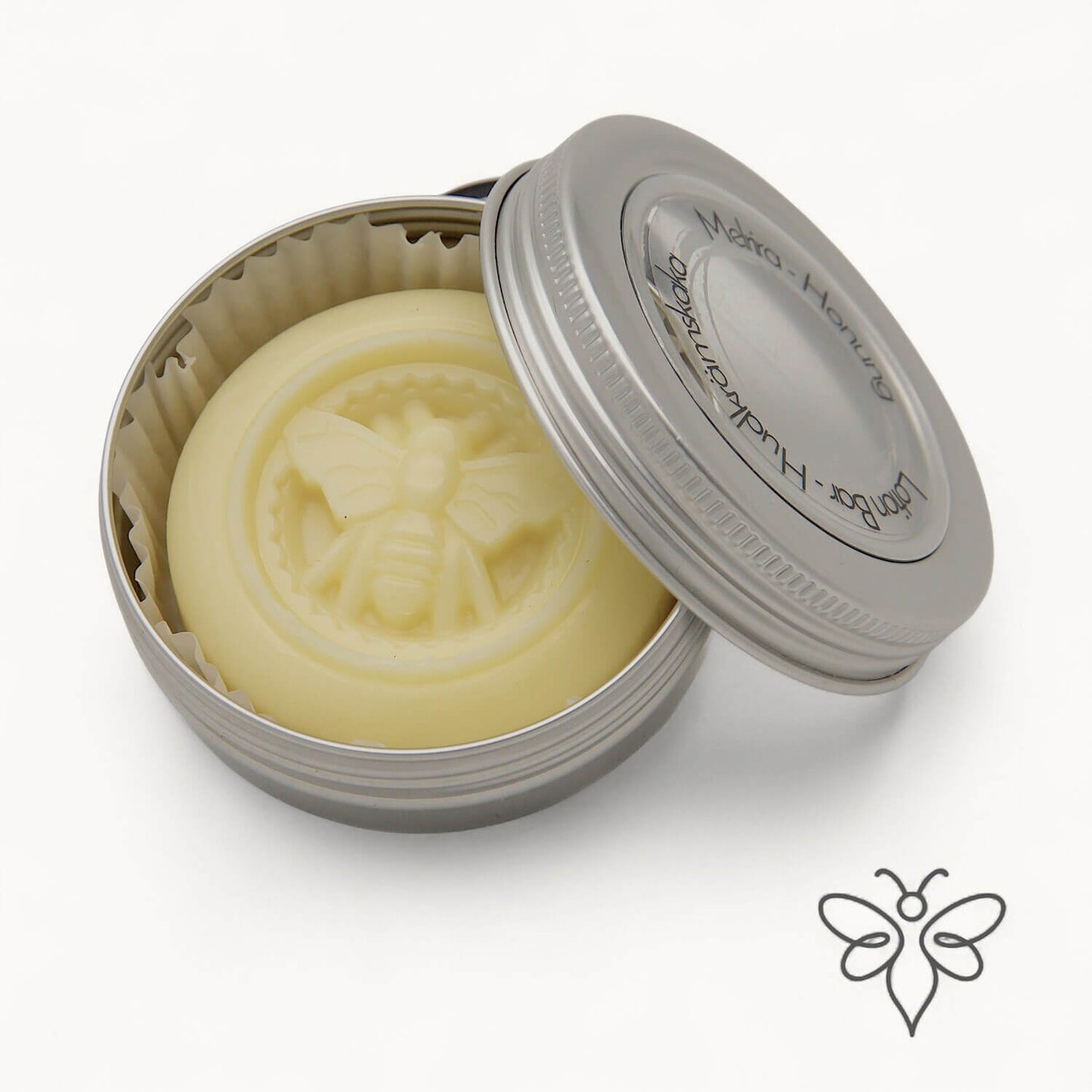 EneboBee Hudkrämskaka – Lotion Bar med bivax i doften Melira i en öppnad metallburk med locket lutad mot en silverfärgad burk.