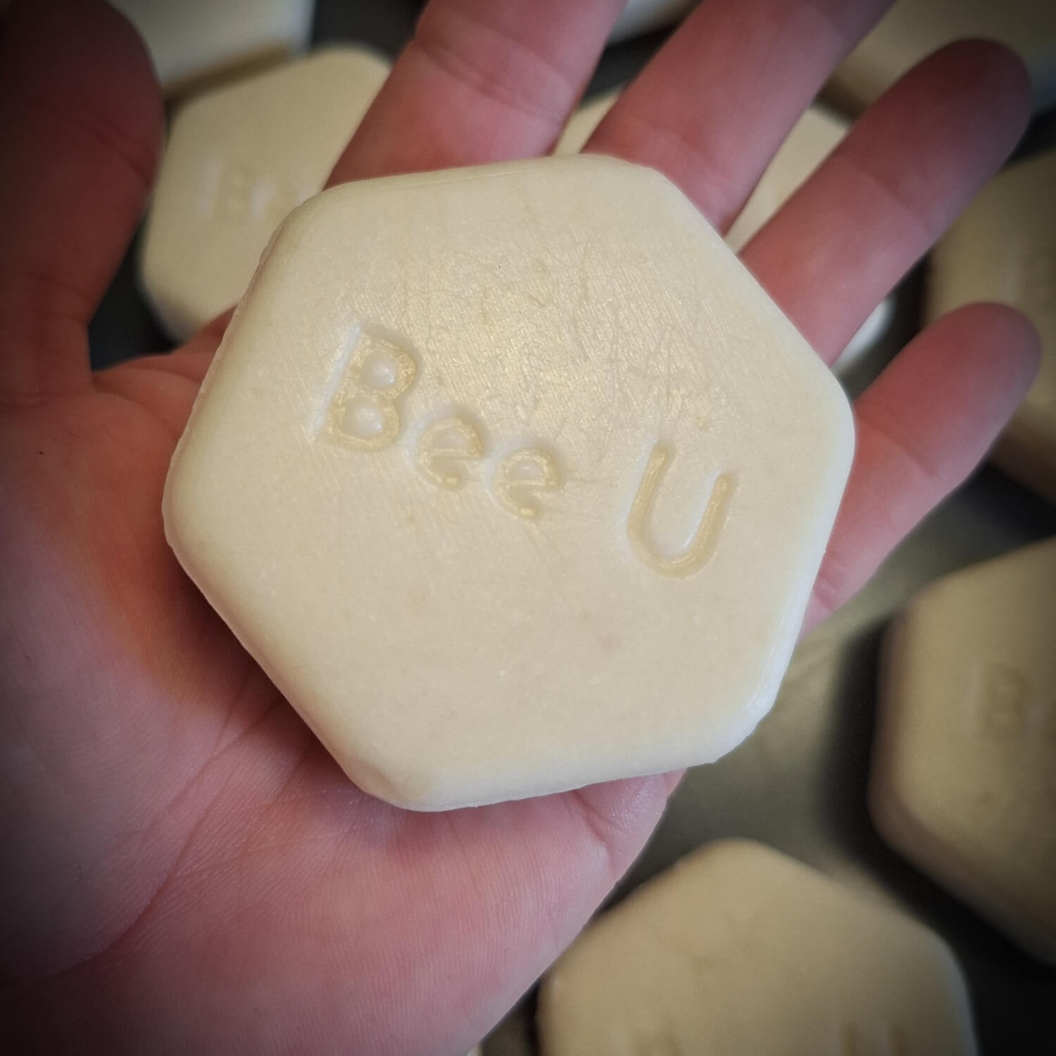 En cremfärgad hexagonformad Schampokaka – Honungsschampo i– Omsorg Alba, i en hand