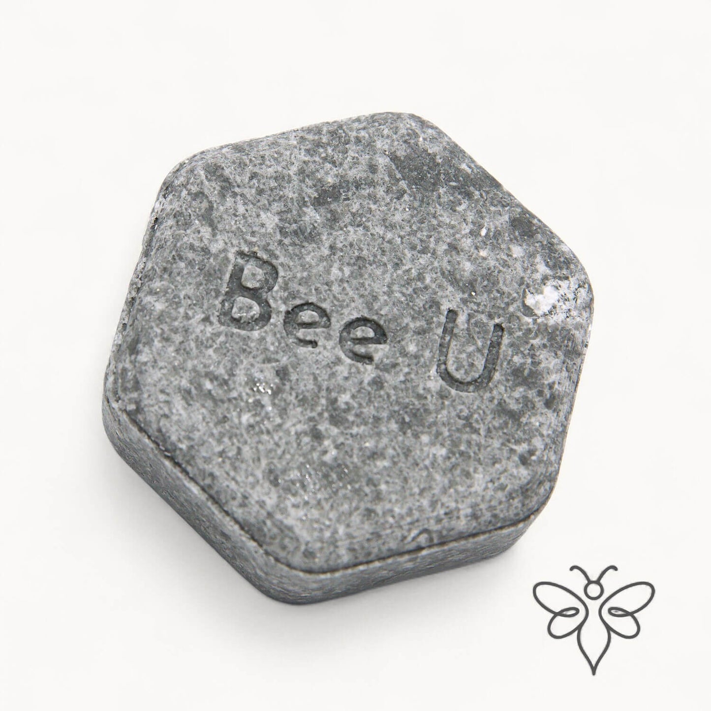 EneboBee schampokaka Omsorg Carbo, handgjort honungsschampo, en gråmelerad hexagon.