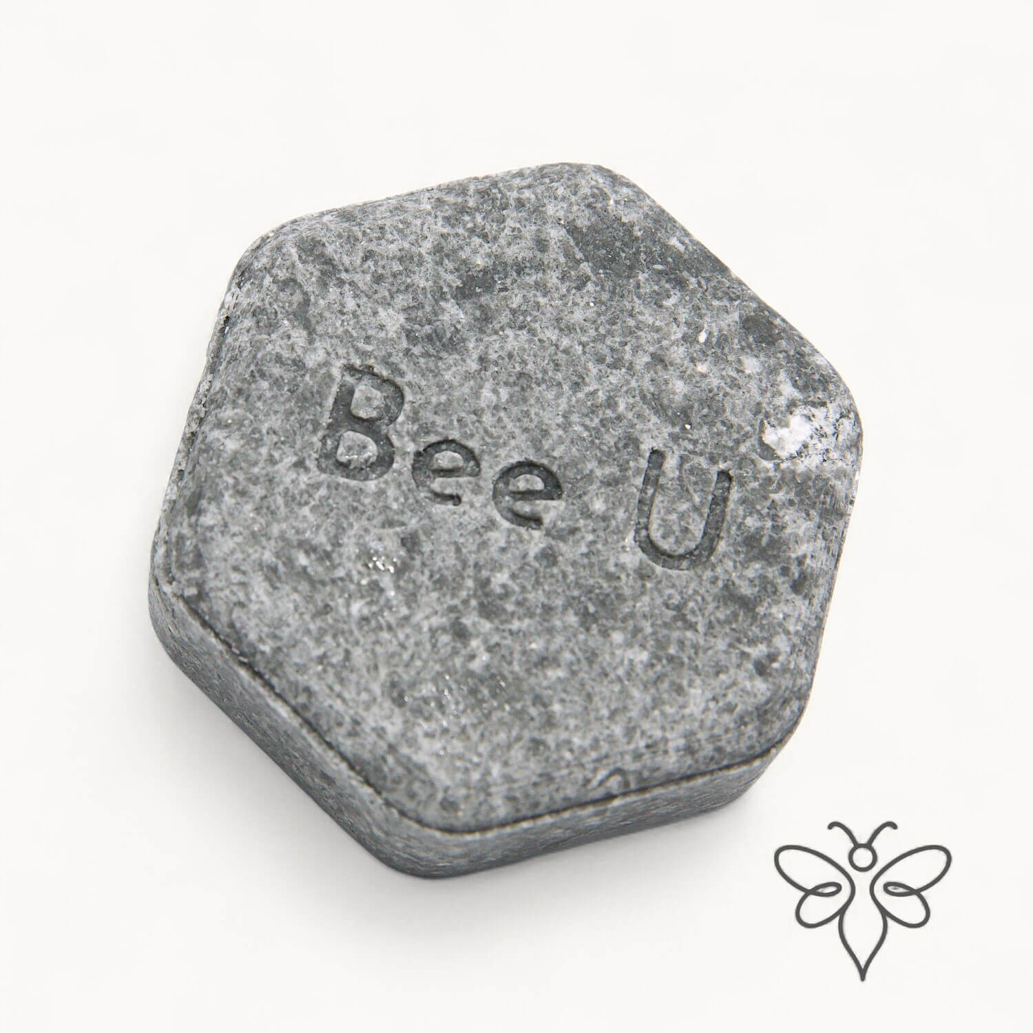 EneboBee schampokaka Omsorg Carbo, handgjort honungsschampo, en gråmelerad hexagon.