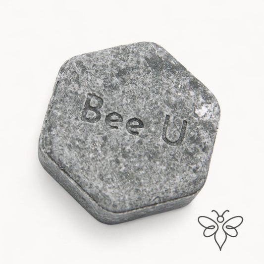 EneboBee schampokaka Omsorg Carbo, handgjort honungsschampo, en gråmelerad hexagon.